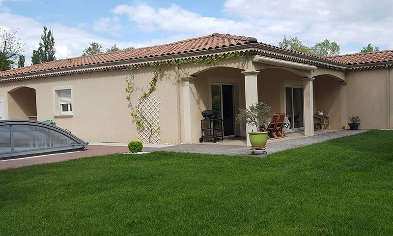 Vue de côté d'une villa plain pied construite par BELCASTRO, dôme piscine et lierre grimpant sur la façade.