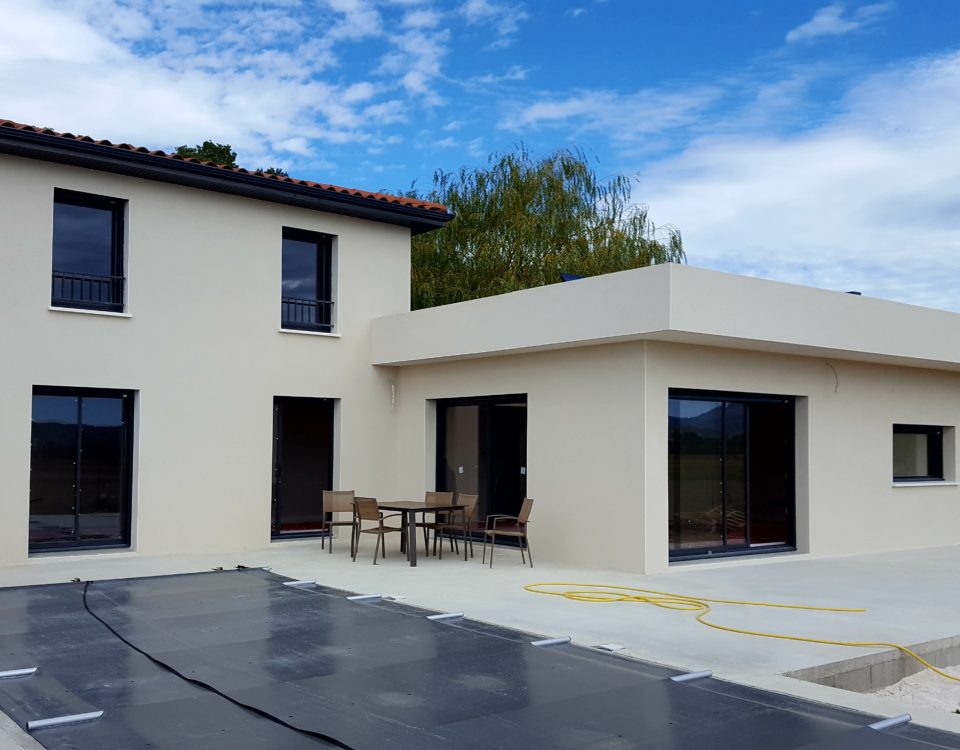 Vue d'une maison façade blanche, piscine couverte avec toit 4 pans et toit plan, réalisation BELCASTRO.