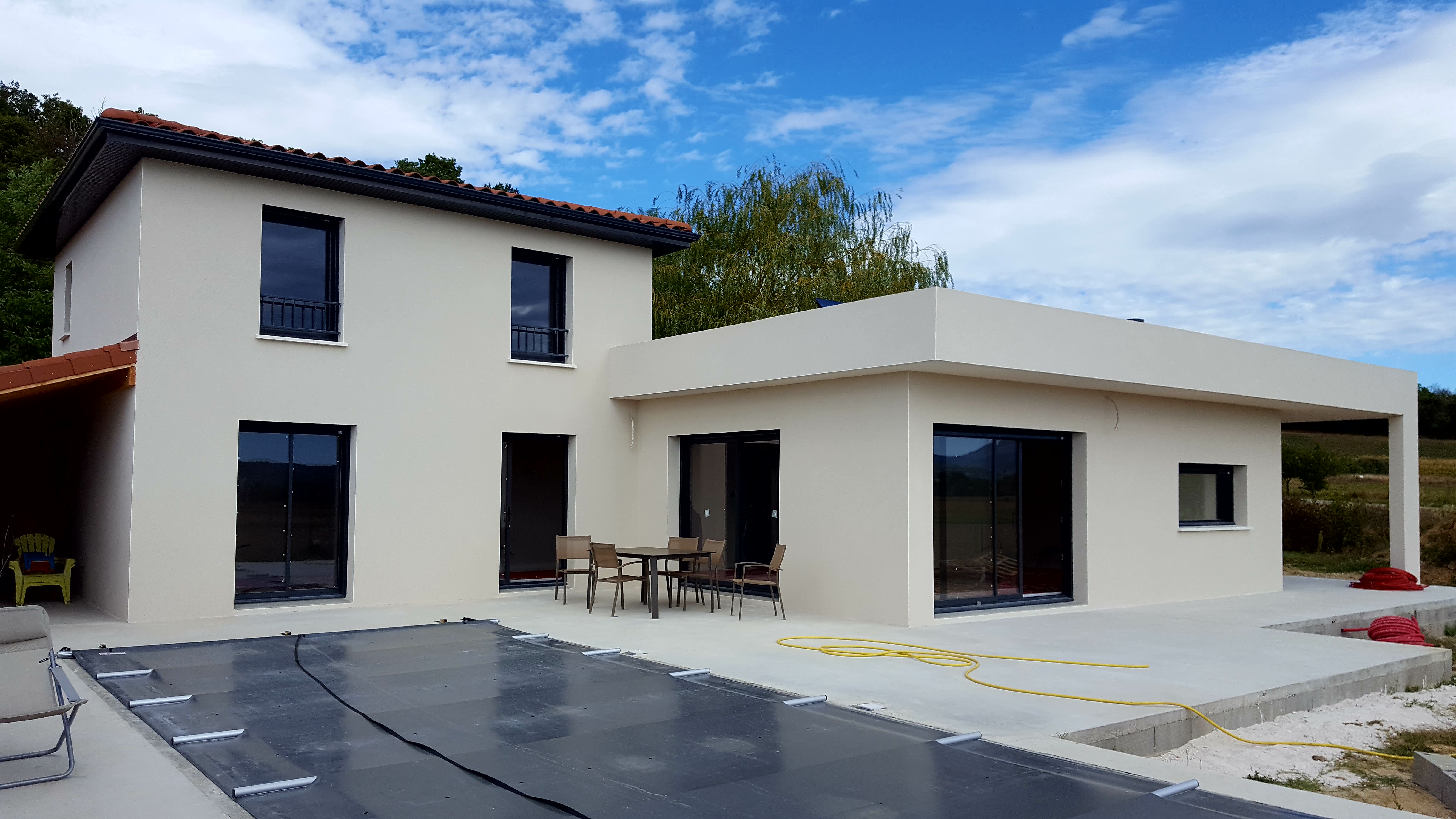 Vue d'une maison façade blanche, piscine couverte avec toit 4 pans et toit plan, réalisation BELCASTRO.