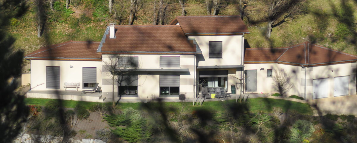 Vue sur la façade blanche d'une villa à travers la végétation, une réalisation BELCASTRO.