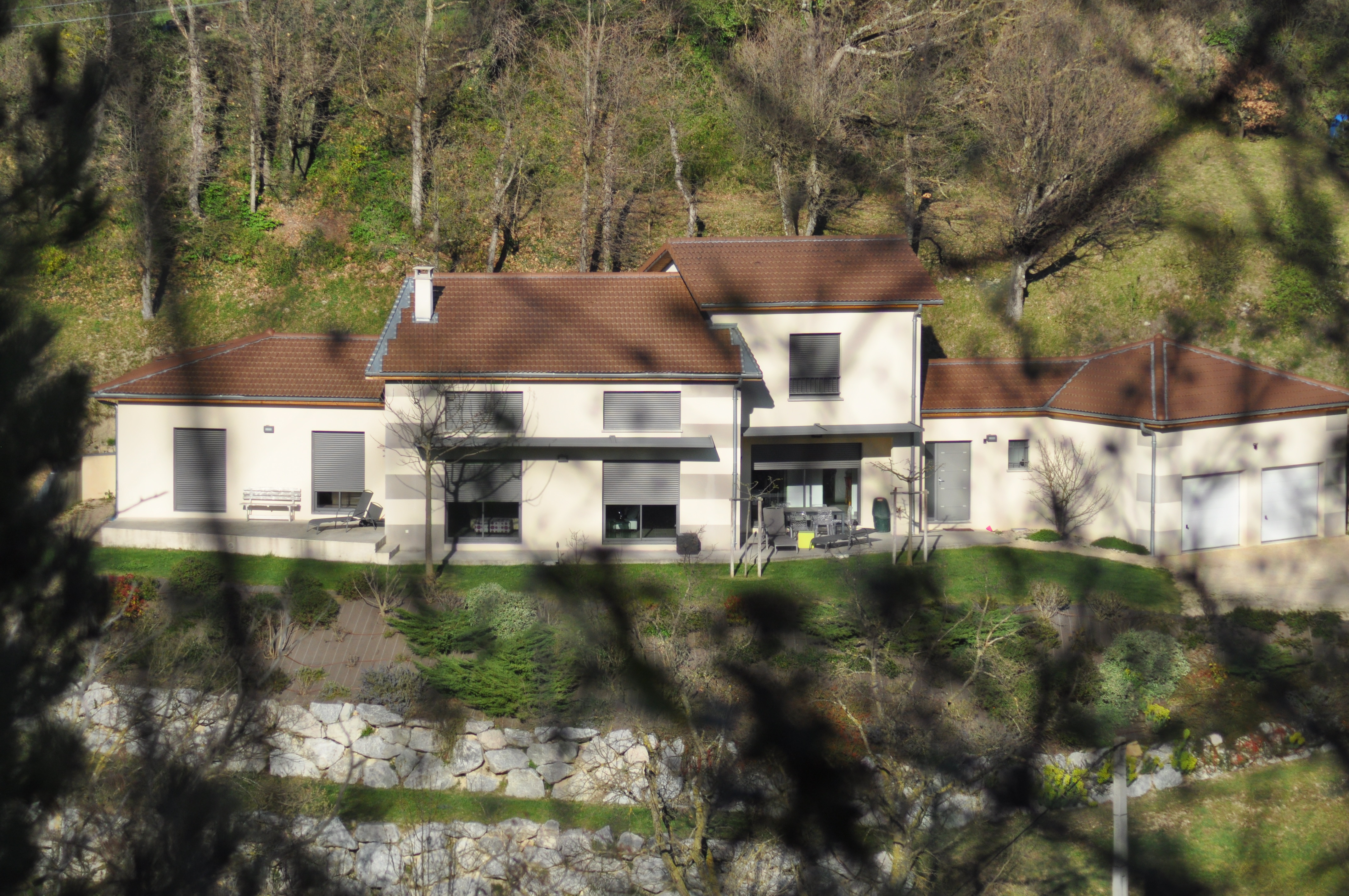 Vue sur la façade blanche d'une villa à travers la végétation, une réalisation BELCASTRO.