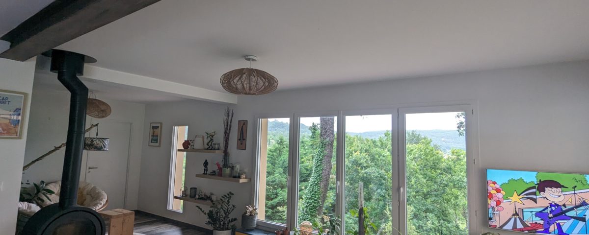 Une réalisation d'agrandissement salon avec grand espace lumineux et fenêtre, poêle, canapé gris par BELCASTRO.